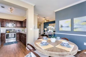 Kitchen with stainless steel appliances, dining area with 4 seats, and living room with blue accent walls
