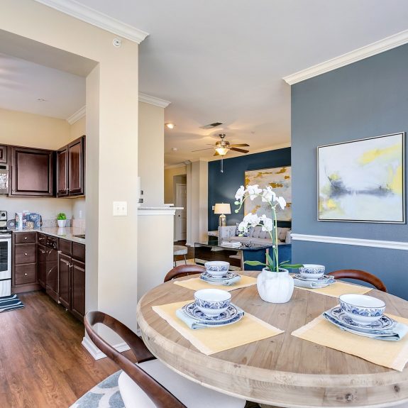 Kitchen with stainless steel appliances, dining area with 4 seats, and living room with blue accent walls