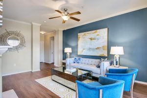 Living room with blue accent wall, ceiling fan, fireplace, and hardwood style flooring