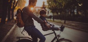Dad and toddler son on bike in suburban park