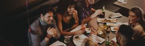 Diverse group dining in fine restaurant and laughing over drinks