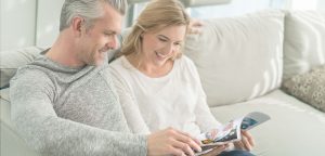 Couple sits on couch reading magazine together