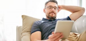 Man on couch reading on tablet