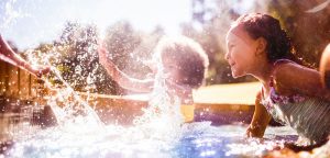young girls splashing in a sunny pool