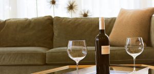 Wine bottle and glasses sitting on table in front of couch