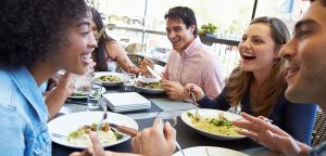 Diverse friends laugh over meal outdoors at a restaurant