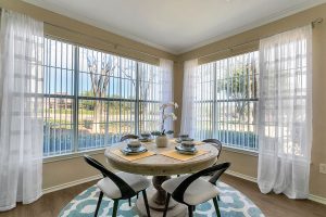 Dining area with 4-person round table and 2 very large windows overlooking landscaping