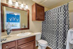 Bathroom with one sink, cabinet space below sink and above toilet, large mirror, and tub