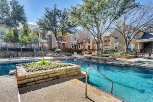 Pool with lounge chairs, landscaping and trees